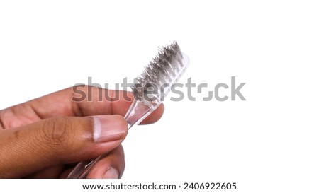Close-up view of a man's hand holding transparent colored toothbrush with dirty brush surface filled with dust and dirt isolated on white background.