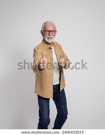 Portrait of smiling senior male entrepreneur in eyeglasses gesturing thumbs up on white background