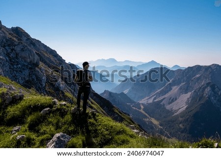 Hiker man with scenic view of mountain peak Grintovec, majestic Kamnik-Savinja Alps, Slovenia, Europe. Magnificent hiking trail in untamed Karawanks, Austrian border. Magical mountains Slovenian Alps Royalty-Free Stock Photo #2406974047
