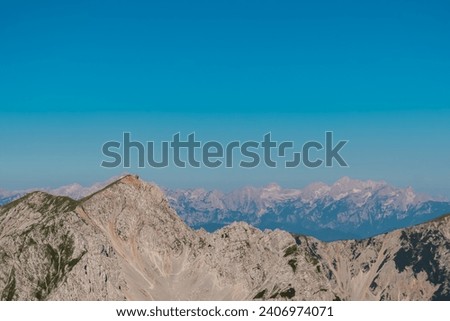 Scenic view of majestic mountain peak Hochstuhl (Stol) in untamed Karawanks, border Slovenia Austria. Looking from Vertatscha peak. Hiking wanderlust in wilderness of Slovenian Alps in summer Royalty-Free Stock Photo #2406974071