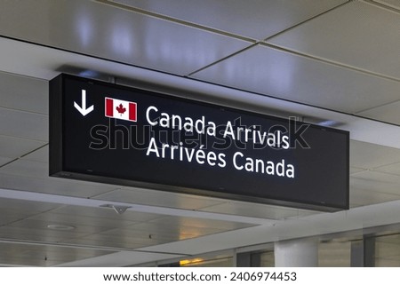 Airport sign indicating Canada Arrivals in English and French with an image of the Canadian Flag Royalty-Free Stock Photo #2406974453