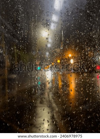 Rain bokeh road lights. Abstract shot of evening city traffic bokeh. Multicolored lights of the evening city and passing cars through a wet rainy window. Royalty-Free Stock Photo #2406978975