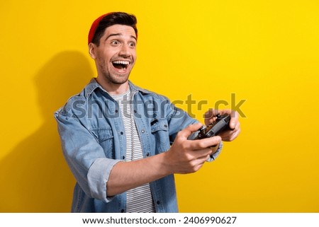 Photo of funny excited man dressed jeans shirt enjoying playstation game empty space isolated yellow color background