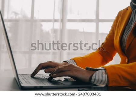 Business woman using mobile phone during working on laptop computer, surfing the internet, searching business data at modern office. Asian businesswoman online working on computer at workplace