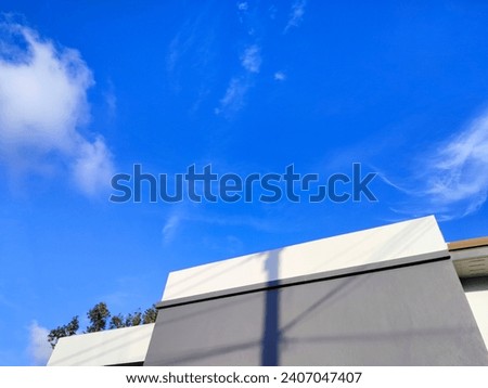A picture of a deep blue sky that turns blue. The clouds are venting just right. Above the roof of a vintage style house Man-made and nature-made
