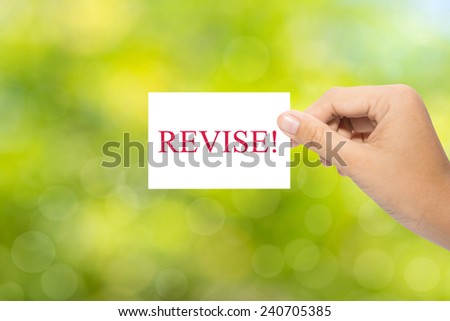 Hand holding a paper REVISE! on green background 