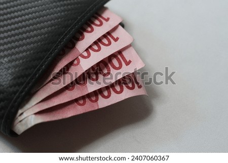 Indonesian money in a black Wallet on White background.IDR 100,000.