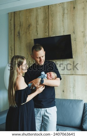 Woman and man holding a newborn. Mom, dad and baby. Close-up. Portrait of young smiling family with newborn on the hands. Happy family on a background.