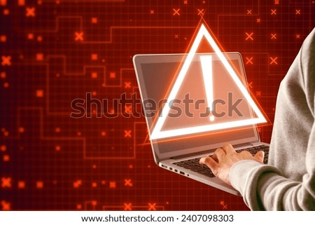 Hacker using laptop with creative red security alert on blurry background. Fraud and danger concept