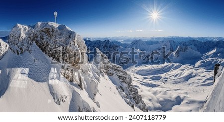 Breathtaking panoramic view from the Zugspitze summit on the Alps on a frosty winter day. Bright sun on the background of the blue sky. Bavarian Alps, Germany. Zugspitze Ski Resort