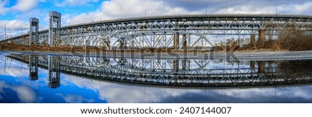 Gold Star Memorial Bridge in New London, Connecticut, the arching landmark suspending bridge over the Thames River, reflected symmetrical shapes over the water Royalty-Free Stock Photo #2407144007