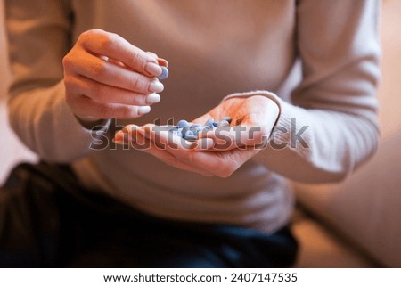pills in young woman hand. Female hand sorting pills on brown background