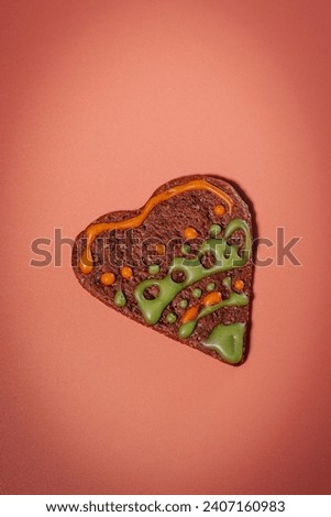 Colorful heart-shaped cookie-gingerbread on a pink background for Valentine's Day. Heart-shaped gingerbread on a pink background. Love and prosperity. Gingerbread with a frosted surface.