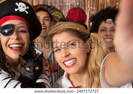 Friends make self-portraits with Brazilian carnival costumes. Pirate woman holds a black cat. Group of brazilian friends partying in a nightclub.
