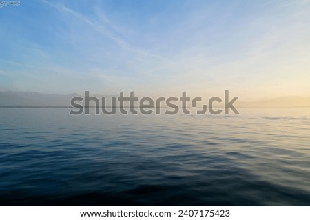 the tranquil transparent waters of lake Constance (Bodensee) with the Swiss Alps in the background on a calm October day on Lindau island, Germany Royalty-Free Stock Photo #2407175423