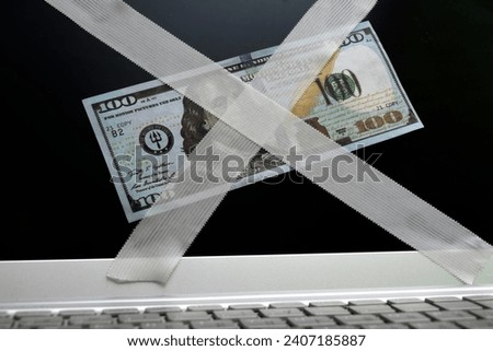 A hundred-dollar bill pasted on the laptop monitor screen with a Band-Aid. The concept of online trading.