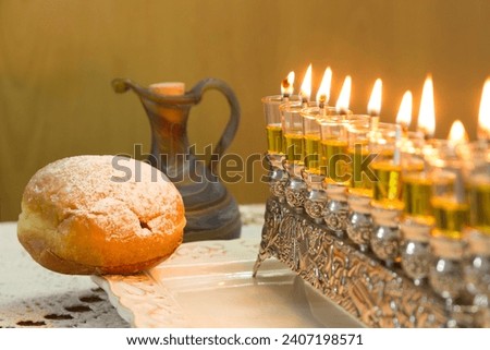 Hanukkah candlestick lit with olive oil and a bun sprinkled with powdered sugar
