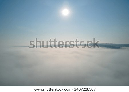 Aerial view from high altitude of earth covered with white puffy cumulus clouds on sunny day Royalty-Free Stock Photo #2407228307