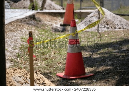 Yellow warning cones and tape as protective restriction barrier at industrial construction site. Safety for pedestrians