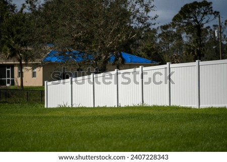 White vinyl picket fence on green lawn surrounding property grounds for backyard protection and privacy Royalty-Free Stock Photo #2407228343