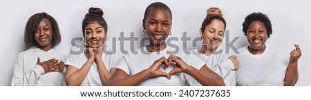 Horizontal shot of cheerful women make heart gesture show korean like sign and express gratitude smile pleasantly dressed in casual clothing isolated over white background. Body language concept