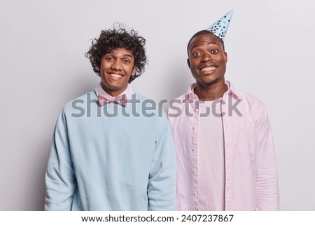 Portrait of two cheerful guys stand glad dressed in festive clothing smile happily wear festive clothing party hat wait for guests on party isolated on white background. Holiday celebration concept