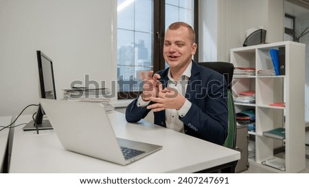 Caucasian deaf man talking sign language over video call on laptop in office.