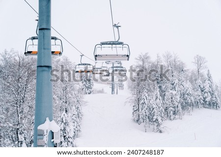 Quadruple chairlift on the slope of a snow-capped mountain Royalty-Free Stock Photo #2407248187