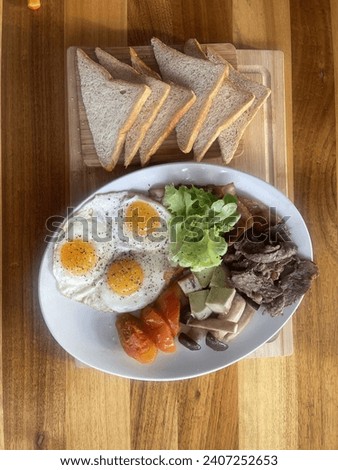 This is a picture of steak and eggs breakfast on a wood table