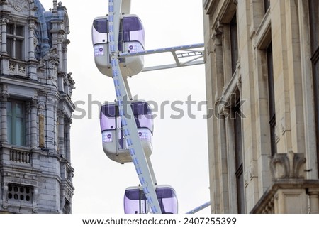 This image captures a modern Ferris wheel juxtaposed against the historic architecture of Antwerp's railway station. The photograph contrasts the playful and contemporary design of the Ferris wheel