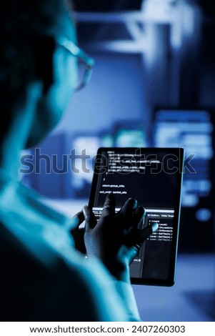 Close up of admin building firewall protection in server room housing advanced infrastructure. High tech workplace manager runs code on tablet to upgrade data center rigs, blurry background Royalty-Free Stock Photo #2407260303