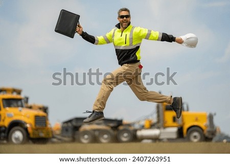 Construction man excited jump with helmet. Builder in helmet outdoor portrait. Worker in hardhat. Construction engineer worker in builder uniform on construction. Excited foreman jump. Royalty-Free Stock Photo #2407263951