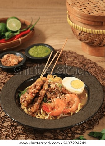 Mie rebus medan or Noodle Soup The dish is made of yellow egg noodles, which are also used in Hokkien mee, with a spicy slightly sweet curry-like gravy. Served with chicken sate, boiled egg, shrimp
 Royalty-Free Stock Photo #2407294241