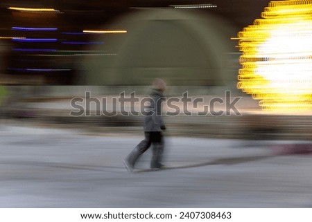 Blurred portrait of young girl ice skating on a large ice rink in public park in evening. Long exposure, defocused, motion. Royalty-Free Stock Photo #2407308463