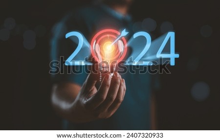 Businessman holding light bulb with target 2023 to 2024 for preparation happy new year concept. New business in new years, start up, action plan and strategy in new business. Royalty-Free Stock Photo #2407320933