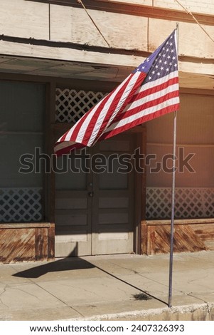 American flag flying outside a building on a main street.