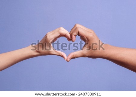Male and female hands forming a heart shape isolated on gray background Royalty-Free Stock Photo #2407330911