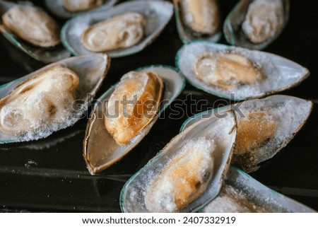 Frozen mussels on black plate. Royalty-Free Stock Photo #2407332919