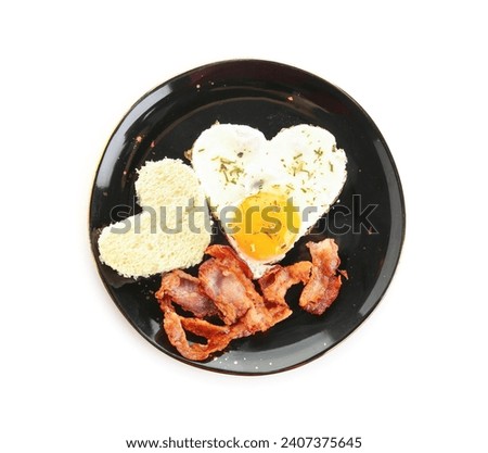 Plate with tasty bacon, hearts made of fried egg and bread piece on white background