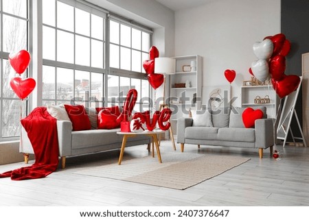 Interior of living room decorated for Valentine's Day with sofas and heart-shaped balloons Royalty-Free Stock Photo #2407376647