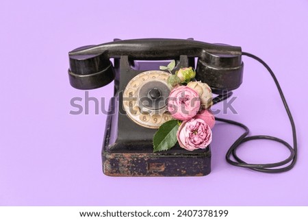 Retro telephone with beautiful flowers on lilac background