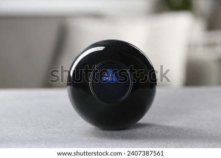 Magic eight ball with prediction Very Likely on light gray table, closeup
