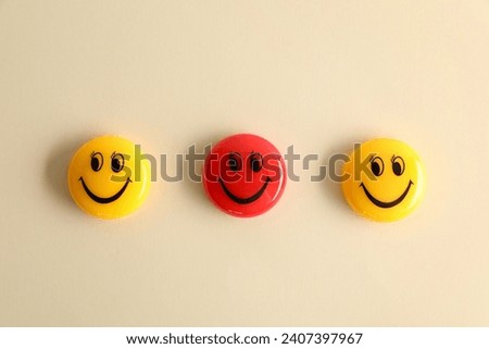 Choice concept. Red and yellow magnets with happy emoticons on beige background, flat lay