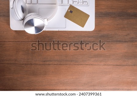 Doing online shopping, online payment with credit card simple background, white laptop with headphones, shopping cart, credit card wooden and light blue background copy space