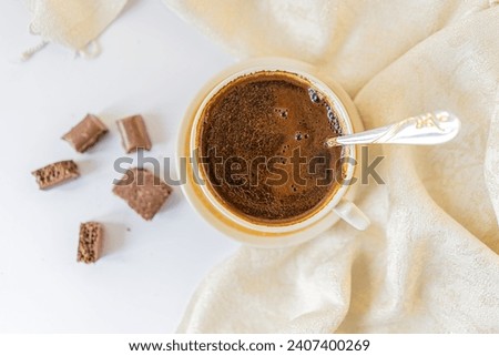 Cup of coffee with chocolate on light white table and beige napkin. Breakfast coffee in bed
