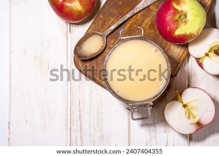 Homemade Organic Applesauce, healthy apple sauce in small jar with fresh summer apples on wooden white background Royalty-Free Stock Photo #2407404355