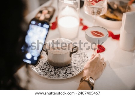 a girl takes a picture of a cocktail in a restaurant. High quality photo