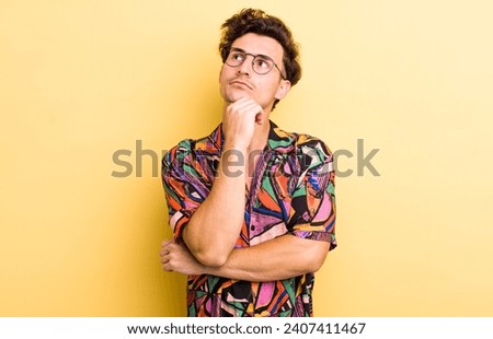 young handsome man feeling thoughtful, wondering or imagining ideas, daydreaming and looking up to copy space Royalty-Free Stock Photo #2407411467