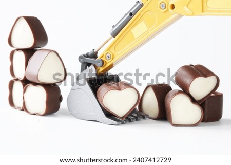 Toy excavator bucket with heart-shaped chocolates. Concept of mining and choosing a love partner, service and dating site. Getting and receiving likes on social networks. Photo. Copy space. Close-up