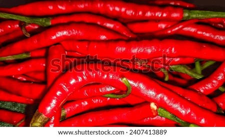 Vibrant red trails of curly chili up close. The fiery hue exudes a captivating visual, hinting at warmth and a spicy flavor ready to tantalize the taste buds. #ChiliPepper #FieryRed #Spicy Royalty-Free Stock Photo #2407413889